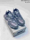 Pair of dark New Balance 9060 mule sneakers displayed on a shoebox, showing the mesh upper, layered overlays, and chunky sole.
