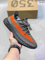 Gray Adidas Yeezy-style sneaker with a bright orange side stripe and dark ridged sole.