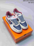 Pair of white, blue and burgundy low-top sneakers displayed on an orange shoe box.
