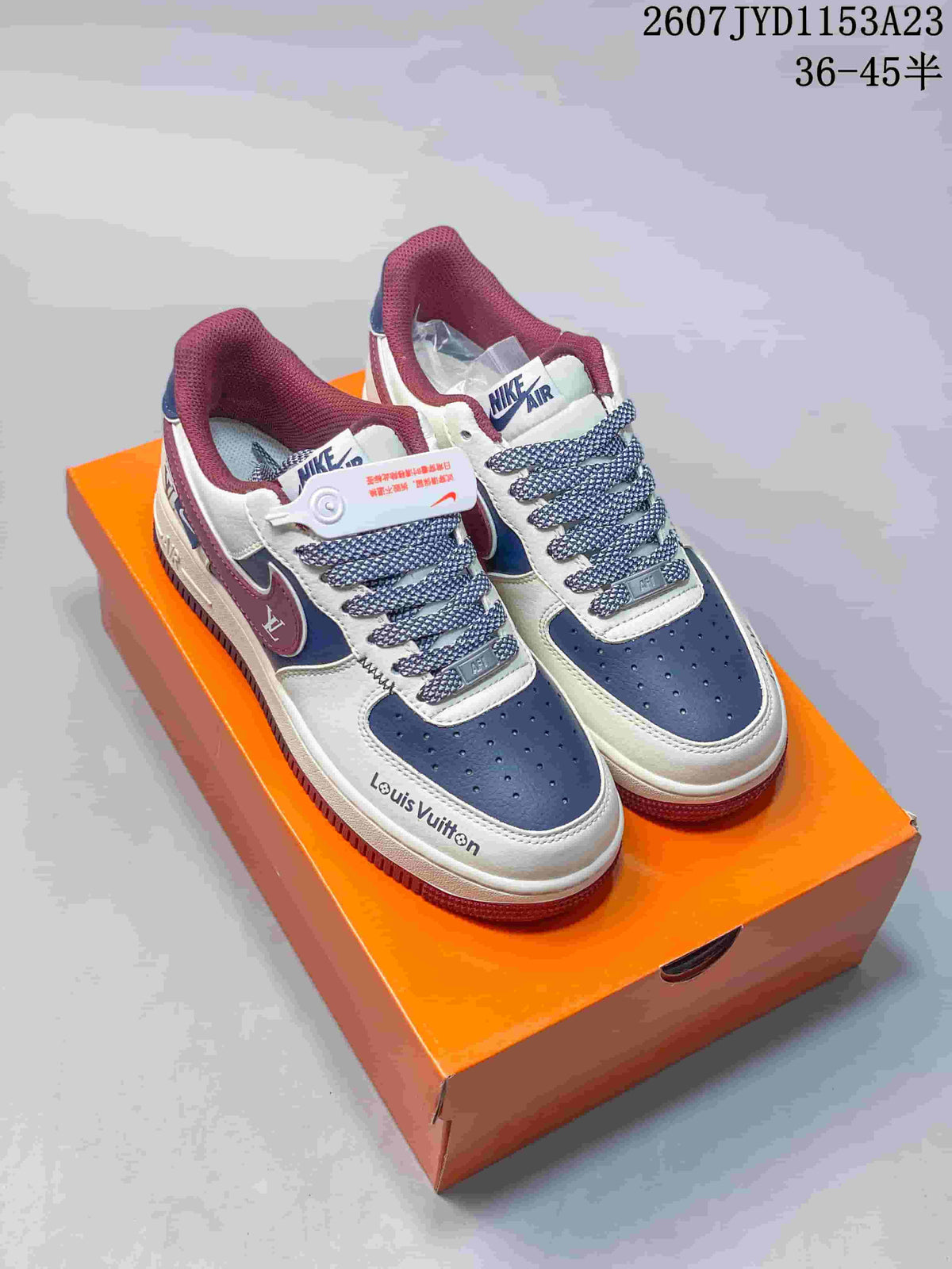 Pair of white, blue and burgundy low-top sneakers displayed on an orange shoe box.
