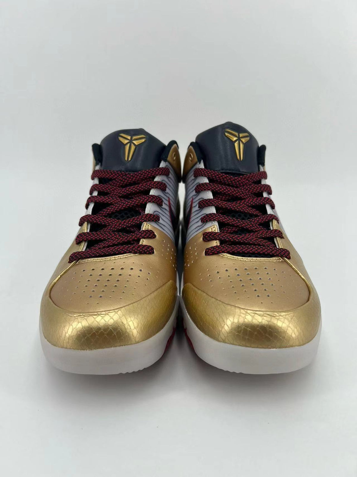 Front view of the pair showing perforated gold toe boxes and red-and-black laces.