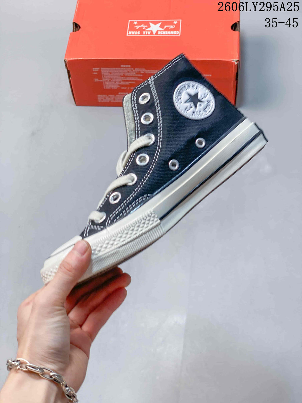 Side view of a navy Converse high-top sneaker with white laces, silver eyelets, contrast stitching and a white rubber sole.